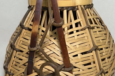 Handcrafted traditional woven bamboo basket with decorative rope knots and a sturdy handle.