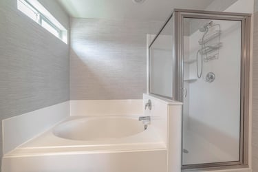 White corner bath and shower cubicle – example of a shower set‑up needing door repair in Auckland