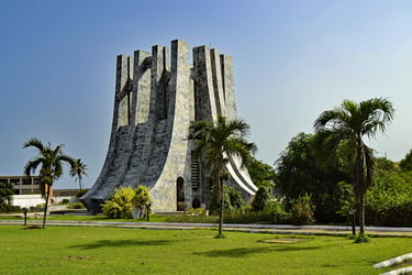 The Kwame Nkrumah Memorial Park and Mausoleum in Accra, Ghana, with palm trees and green grass.