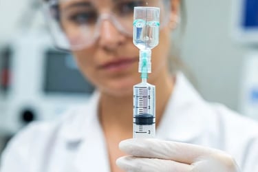 A healthcare professional draws a vaccine liquid from a vial into a syringe in a medical lab setting.