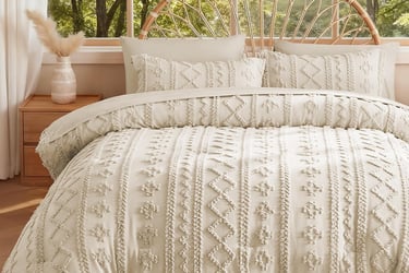 Boho chic cream tufted duvet cover set on a bed with a rattan headboard in a bright bedroom.