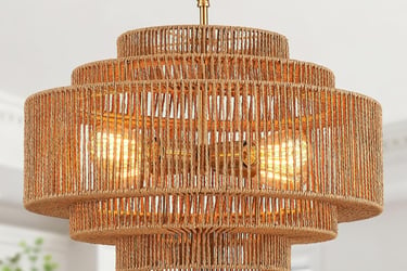 A tiered round jute rope chandelier with glowing Edison bulbs and a gold finish.