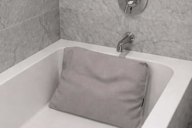 An extra-thick ergonomic bath pillow is displayed inside a white bathtub to show neck support