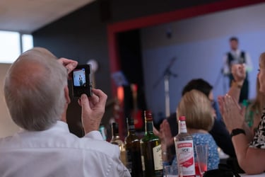 A man records a live musician on a digital camera during a wedding reception dinner.