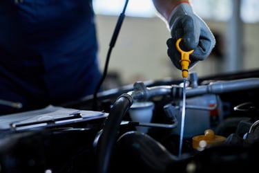 A mechanic holding a yellow dipstick to check engine oil levels during a professional car service.