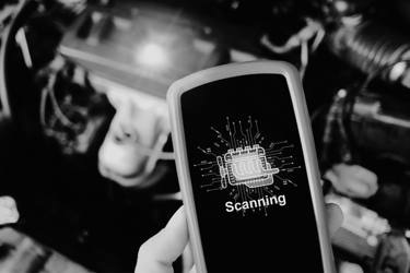 Handheld diagnostic tool scanning a car engine for automotive repair and troubleshooting.