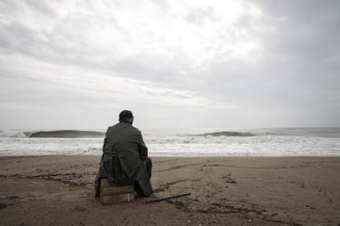 Homme de dos, assis devant le roulement desvaguessur une plage deserte