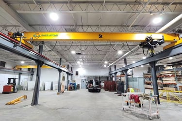 A large, bright yellow overhead bridge crane with SAFE LIFTING