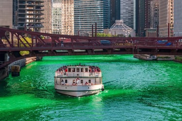 A white tour boat cruises on the bright green Chicago River for Saint Patrick's Day.