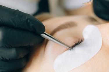 Artista profesional de pestañas aplicando extensiones de pestañas individuales con pinzas y parches