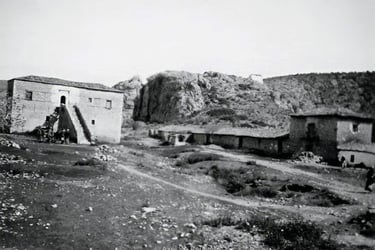 Vintage black and white photo of historic stone buildings and a rocky hillside at Kandia