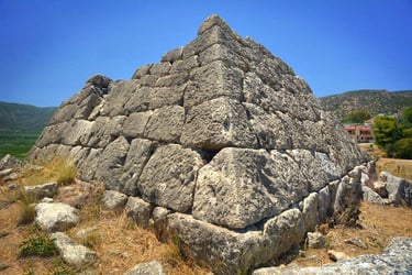 The ancient stone Pyramid of Hellinikon in Greece made of large limestone blocks under a clear blue sky.