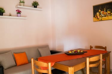 Cozy dining area featuring a wooden table with an orange runner and a grey sofa.