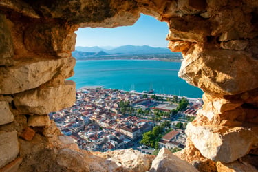 Scenic view of Nafplio city and Argolic Gulf through a stone window at Palamidi Fortress in Greece.