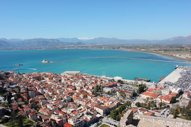 Aerial view of Nafplio city in Greece featuring red roofs, turquoise Argolic Gulf, and Bourtzi castle.