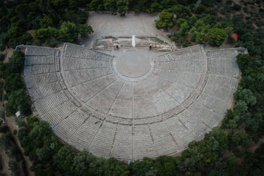 Aerial view of the ancient Theatre of Epidaurus in Greece surrounded by lush green trees.