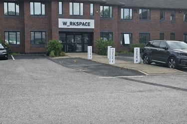 W_RKSPACE shared office building entrance with brick facade and parking lot.