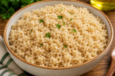 A ceramic bowl filled with cooked brown rice and garnished with fresh parsley on a wooden table.
