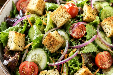 Fresh garden salad with crunchy croutons, cherry tomatoes, cucumbers, and red onion in a bowl.