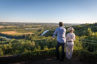 a couple of people standing on a hill overlooking a dordogne valley