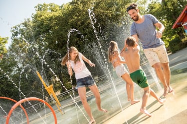 a man and two children playing in a fountain