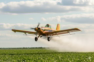 a plane is flying low over a field, embraer emb-200 ipanema