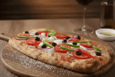 Pinsa romana με λαχανικά και φέτα τυρί σε ξύλινη βάση