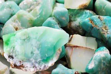 Collection of raw, polished green chrysoprase and teal turquoise gemstones in a close-up pile.