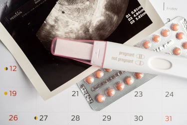 A positive pregnancy test, ultrasound photo, and birth control pills on a calendar.