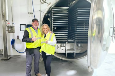 Monty and Debbie standing in front of a very large freeze drier