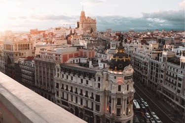 Panoramic skyline view of Madrid architecture featuring the historic Metropolis Building at sunset.