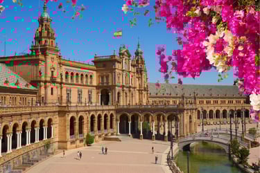 Plaza de Espana in Seville with pink flowers framing the historic Spanish architecture.