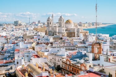 Panoramic view of Cadiz Cathedral and white city buildings along the Spanish coastline.