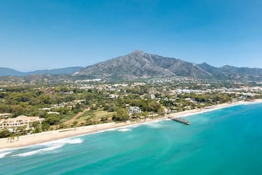 Aerial view of Marbella beach with La Concha mountain under a clear blue sky.