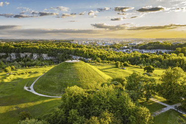 Aerial view of Krakus Mound in Krakow, Poland, surrounded by lush green parkland at sunset.