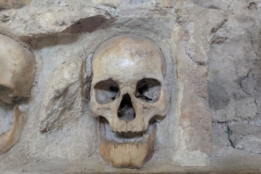 Antique human skull embedded in an ancient stone and mortar wall at a historic catacomb site.