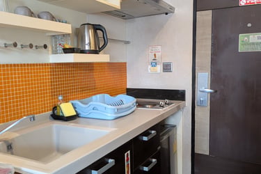 Modern studio kitchenette featuring an orange tile backsplash, microwave, and electric kettle.