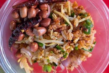 Thai fermented pork salad with peanuts and dried chilies in a plastic bowl Talat Phlu Market.