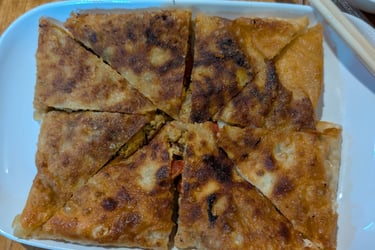 Crispy golden-brown chicken keema prata served on a white plate with dipping sauce and chopsticks.