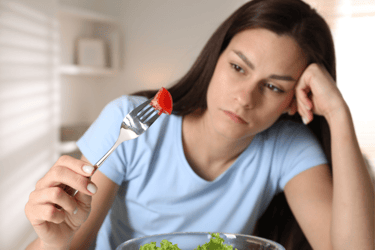 Menina segurando garfo com alimento, mas sem apetite