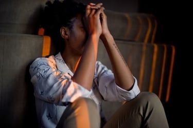 Persona estresada sentada en el suelo con las manos en la cara, lo que representa la salud mental