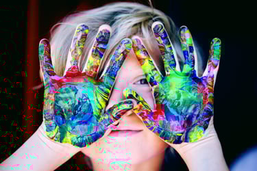 Un enfant joyeux en art-thérapie avec des mains colorées pour créer son œuvre d'art