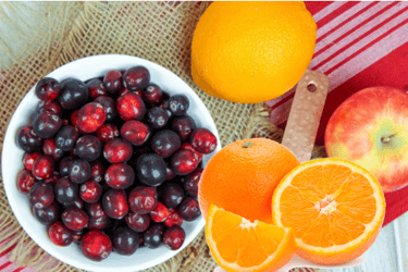 a bowl of cranberries with an oranges and an apple to make fresh cranbery sauce