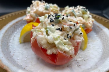 a plate with a crab salad stuffed in a tomato on it
