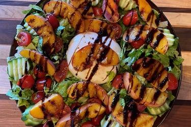 a salad with grilled peaches over burrata and drizzled with balsamic