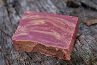 a soap bar with a burgundy and gold swirl design on a tree stump