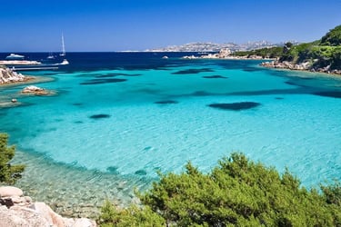 Aerial view of Costa Smeralda’s turquoise waters with luxury yachts anchored near a pristine beach.