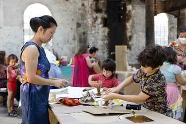 An adult and two children working together on a cardboard structure.