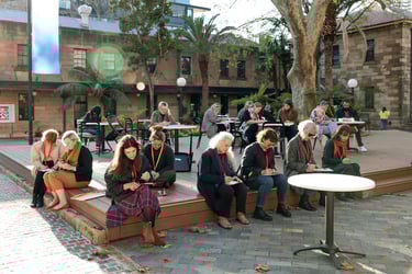 A group of adults sitting outside engrossed in drawing.