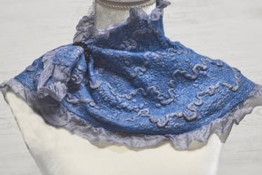 Handmade blue nuno felted wool neck warmer with ruffled edges and textured patterns on a mannequin.